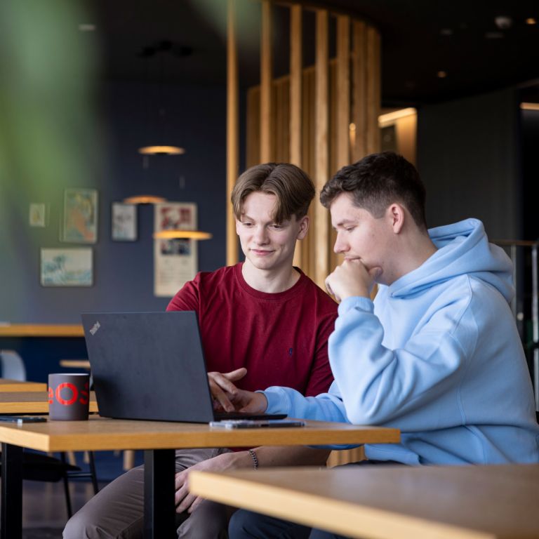 Two young EOS employees examine a computer screen together and discuss what they see. 