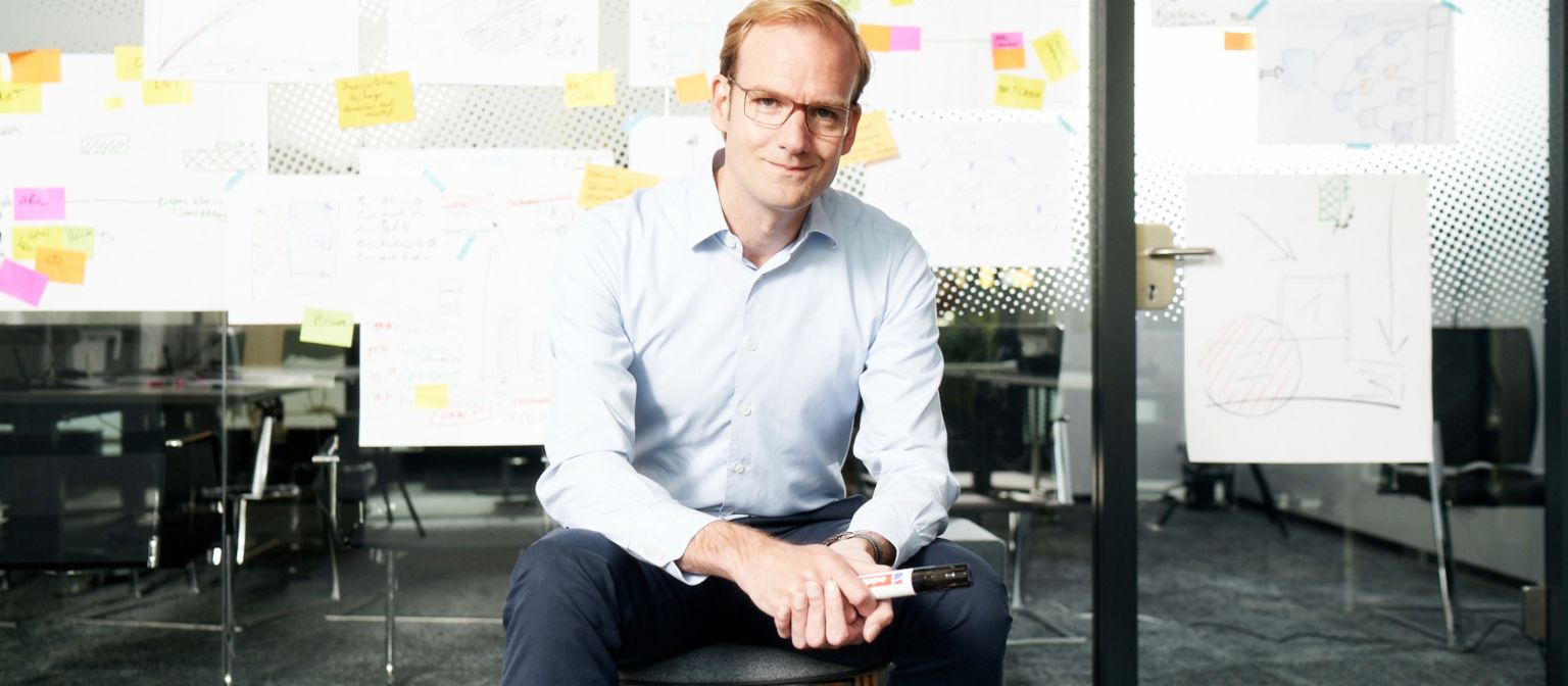 Forderungskauf: Matthias Schmidt, Leiter Operativer Forderungskauf der EOS Gruppe, sitzt vor einer mit Zettel beklebten Wand.