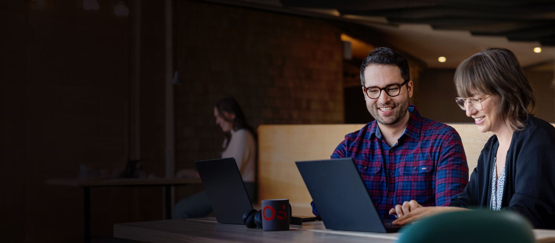 Two EOS employees look at a laptop together while engrossed in a conversation.