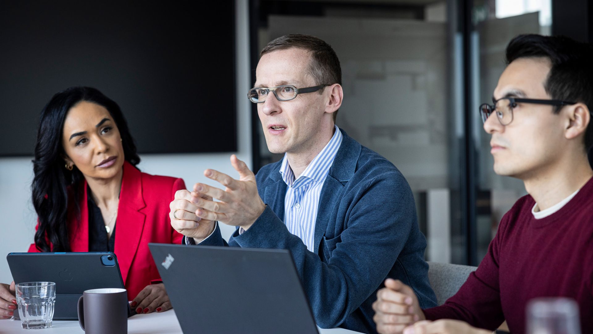  Drei Personen führen ein Gespräch in einem Büro.