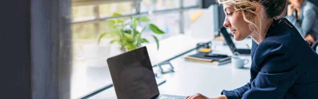 Junge Frau arbeitet an einem Laptop in einem modernen Büro.