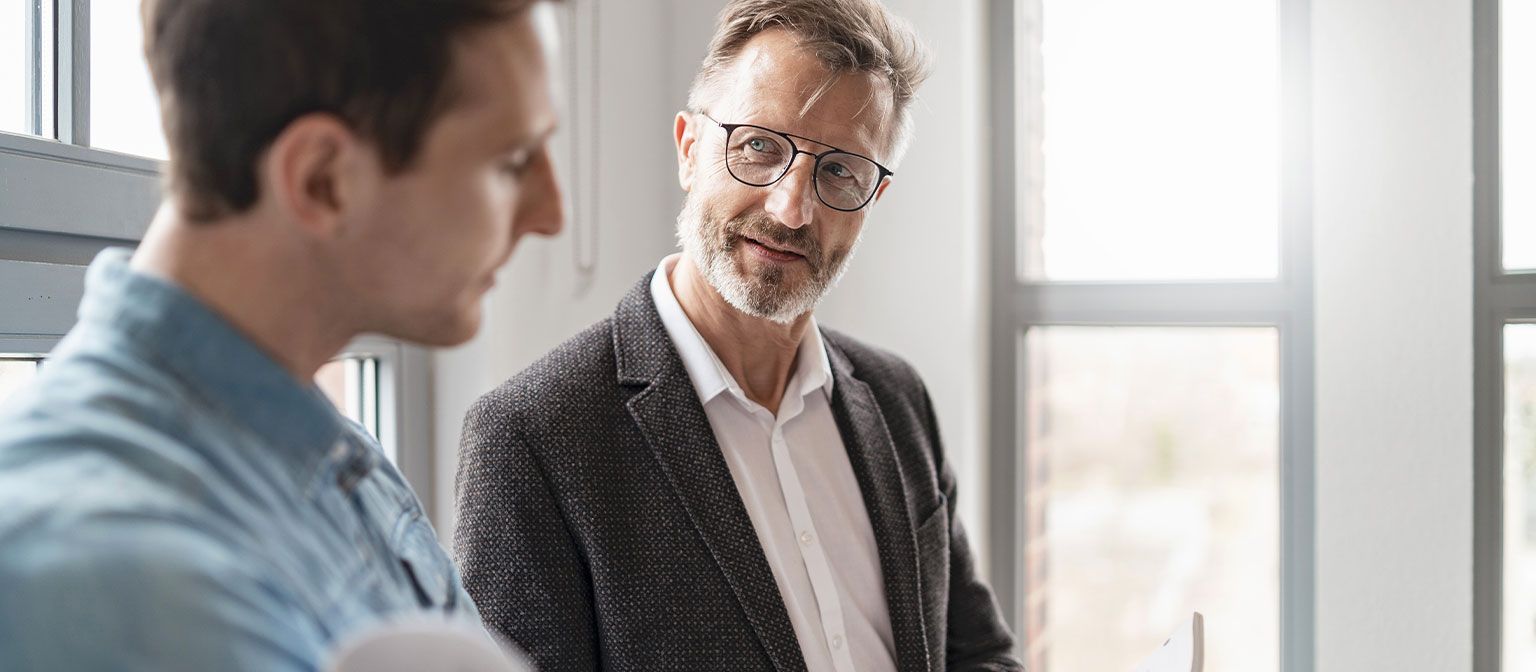 Zwei Männer im Büro sprechen über die Ergebnisse der Studie European Payment Practices 2025 der EOS Gruppe über Digitalisierung im Forderungsmanagement.