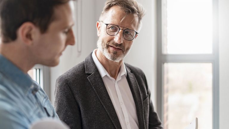 Zwei Männer im Büro sprechen über die Ergebnisse der Studie European Payment Practices 2025 der EOS Gruppe über Digitalisierung im Forderungsmanagement.